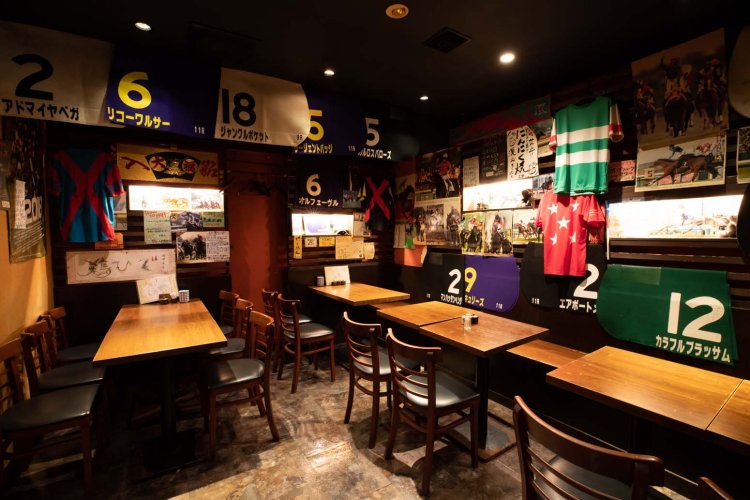 奥のテーブル席。競馬ゼッケンが天井近くまで壁を埋める。
