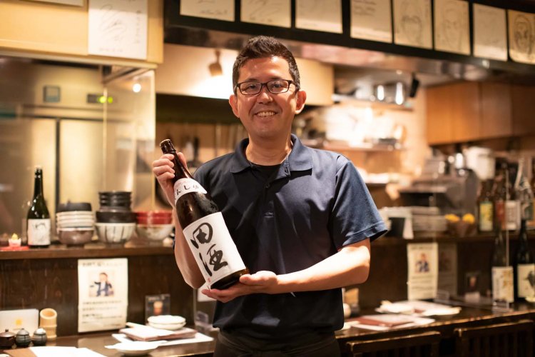 店主の黒田英徳さんは北赤羽出身。手に持っているのは田酒。