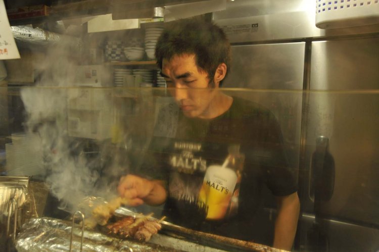 モクモクとした煙の中でもつを焼く店長の小原涼さん。