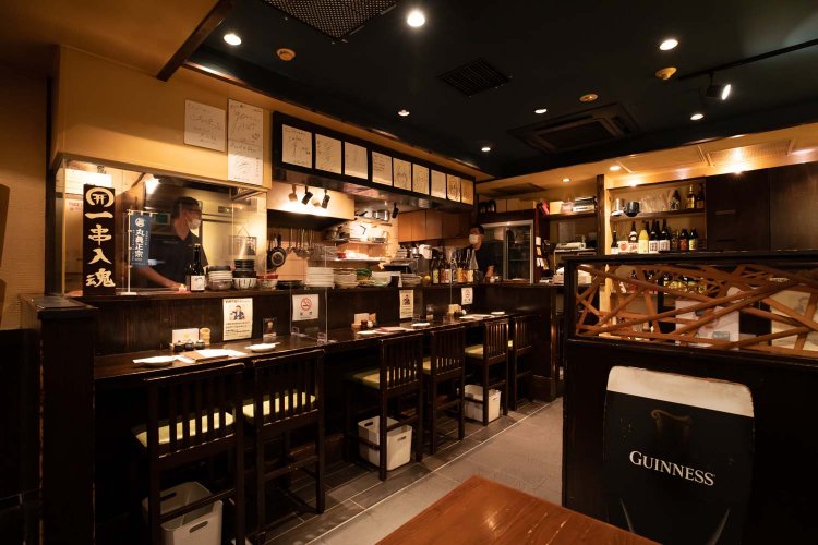 黒を基調としたジャズが流れる空間。カウンター内で焼き鳥を焼く。