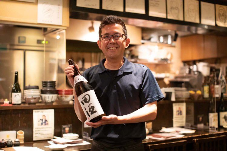 店主の黒田英徳さんは北赤羽出身。手に持っているのは田酒。おすすめの一本だ。