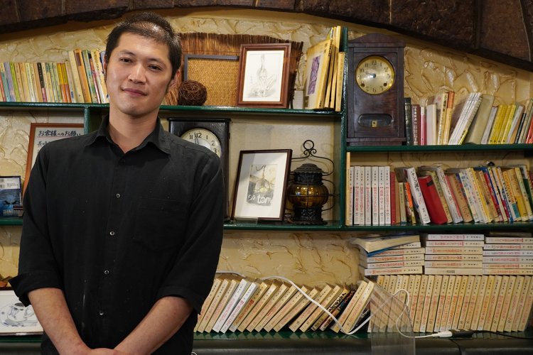 店長の芦澤さん。後ろの本は「友路有図書館」の蔵書で貸し出しが可能。