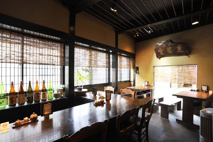 木や竹などを巧みに駆使した純和風の店内。カウンターに、その日に用意された日本酒が並ぶ。