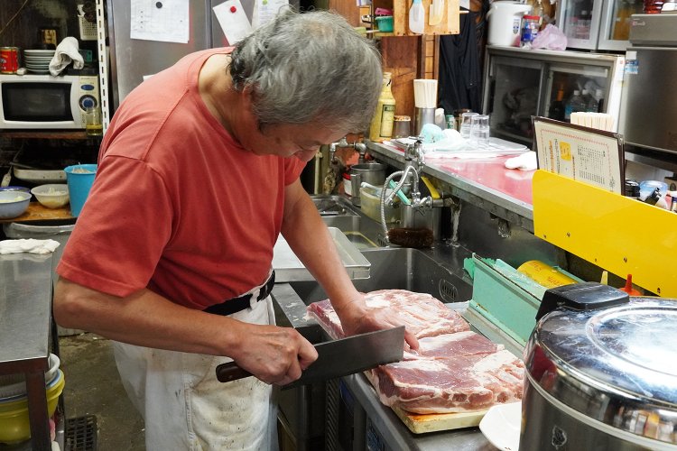 豚バラ肉をチャーシュー用にカットする、店主の佐々木さん。