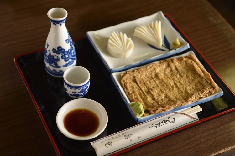 日本酒は「白雪」500円。肴には、そばつゆで煮た油揚げ甘辛煮350円や厚切りの板わさ500円がピッタリ。