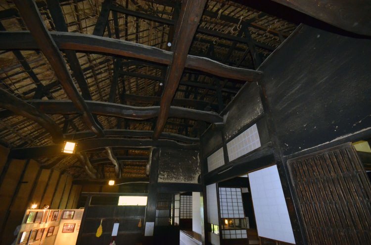 土間の天井の梁組み。三段に組み上げた梁丸太と大黒柱が見える。