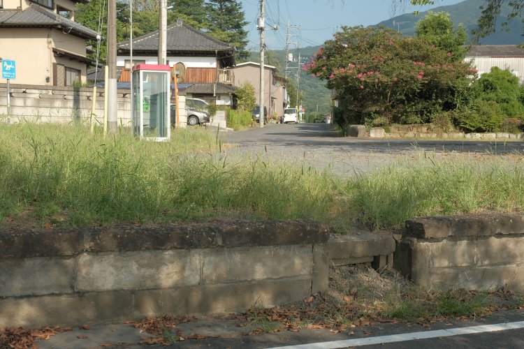 サイクリングロードからホーム越しに見る駅前。ホーム欠き取り部分は職員用の昇降箇所かと思う。駅前は閑静な住宅地である。
