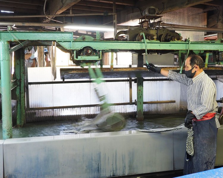 機械が力強く反物を洗って送り出す。水が冷たく、濡れた反物は重いため、冬はかなりの重労働だ。