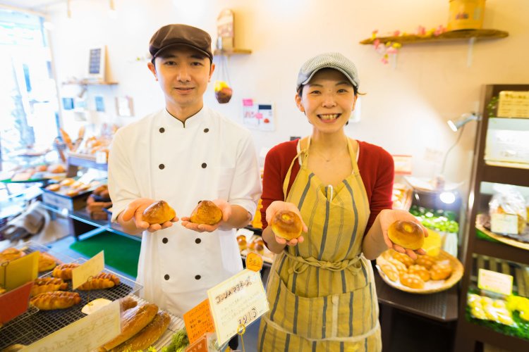 下田さん夫妻。みどりさんが持っているのは、こしあんぱん133円。