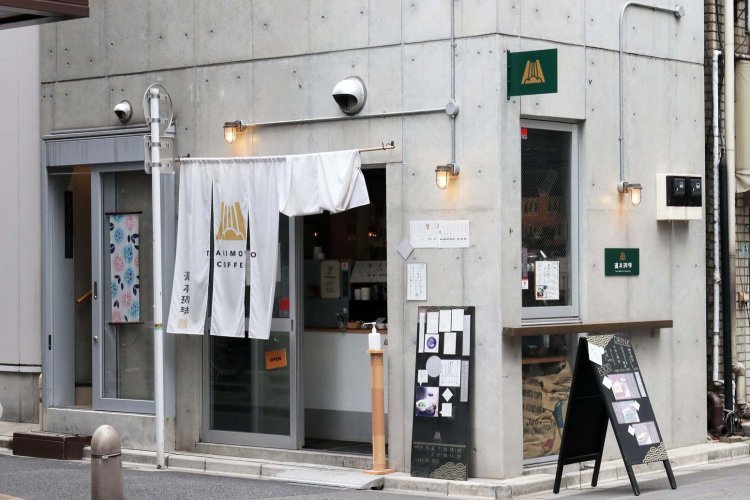 コンクリート打ちっぱなしの3階建てビルで、白い暖簾が目印のコーヒースタンド。