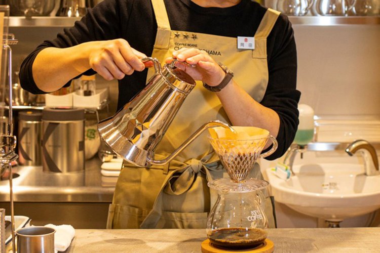 スタッフ着用のエプロンには、コーヒーアドバイザーの証・星バッジが輝く。その場でドリップして淹れたてを飲むことも。