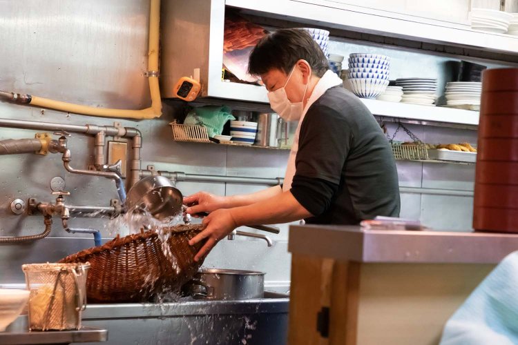 厨房でそばを洗う。次々と注文が入るので手を休める暇はない。