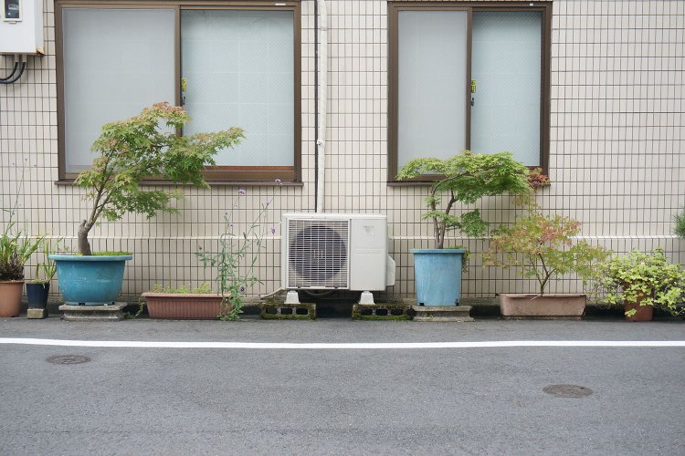 「室外機がセンター」みたいなフォーメーションの植木鉢の配置。室外機を中心に、左右のバランスを考えて配置したのかもしれない。