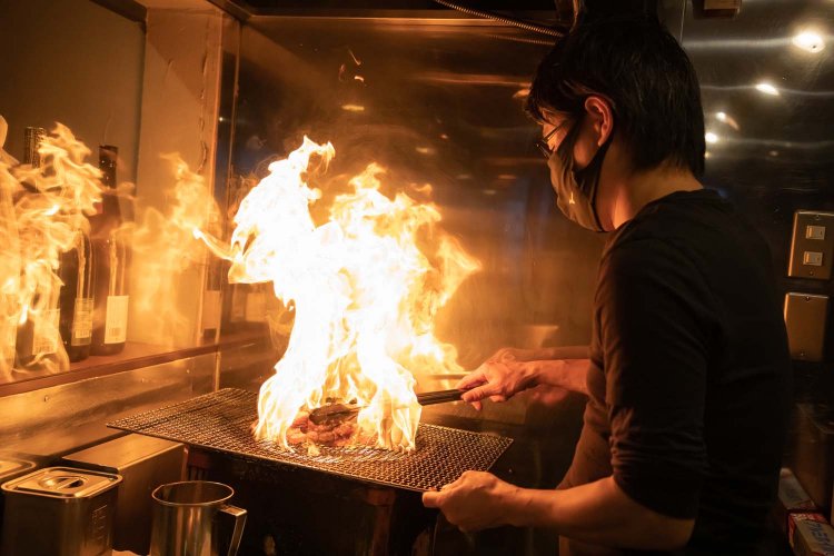 油を注ぐと一気に炎が上がり、煙が立ち上る。熟練の技が必須の調理法だ。