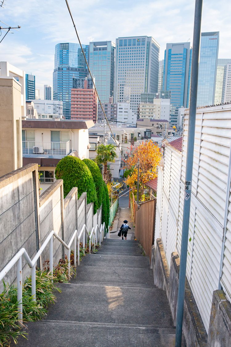 上からは、キヤノンやマイクロソフトなど品川の高層ビル群を眺望。細い階段と都市景観の対比がダイナミック。