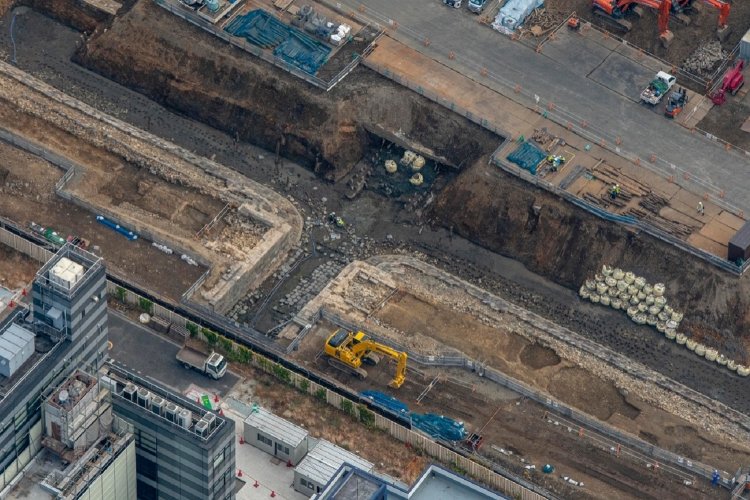 “第七橋梁”を泉岳寺側からみる。ショベルカーがいる側に増線して３線となった。よく見ると、橋台部分は増設したのが判別できる。石垣脇にポツポツとある杭は、築堤が波でさらわれないための防止策。