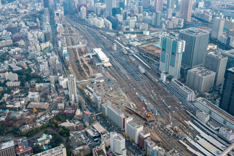 品川駅から高輪ゲートウェイ駅方向をみる。“高輪築堤”は一直線に並ぶビル群の右脇に存在している。堀状になっているのが築堤発掘現場。