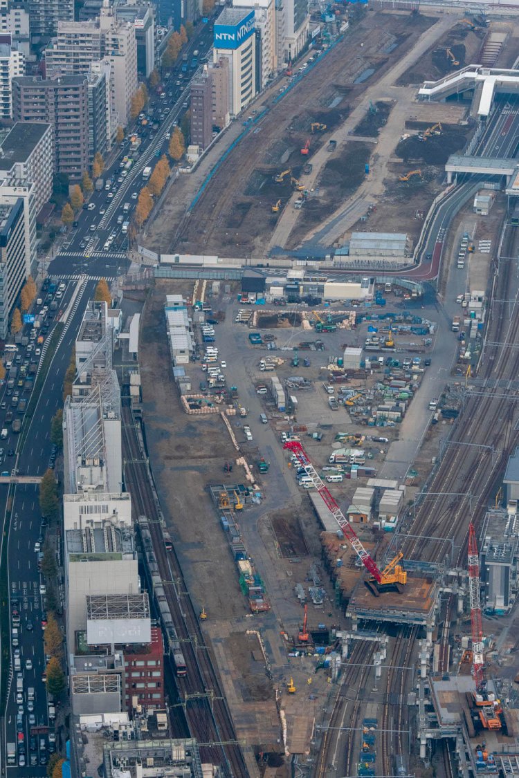 品川駅は手前。京急電車の右隣に築堤が埋まっている。赤白色の大型クレーンの近くでも発掘調査をしている。