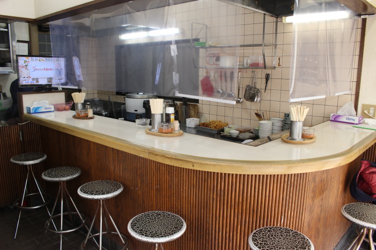 L字型カウンターのみの小ぢんまりした店内。おかみさんと夫の2人で切り回す。