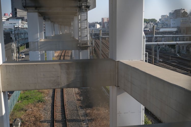 跨線橋の網目から王子駅方向を見やると新幹線高架下に北王子線の錆びた線路がある。