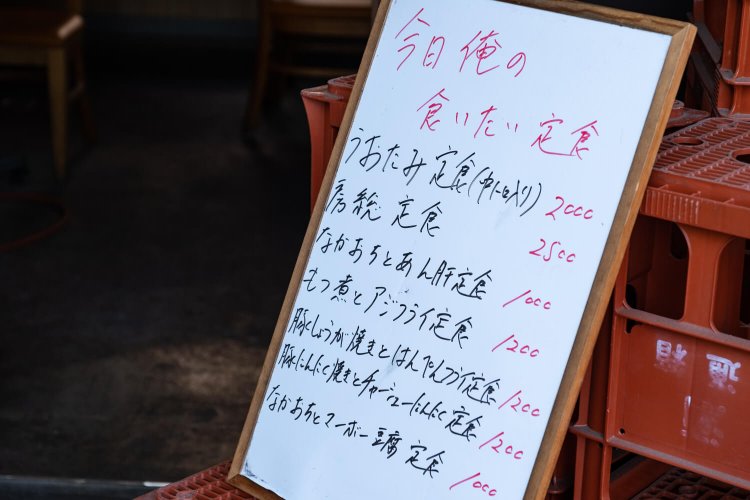 店主の気取らない人柄がうかがえる店頭のボード（価格は税別）。