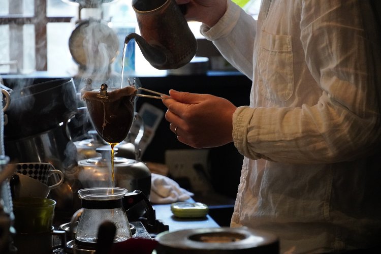 一杯ずつネルドリップで淹れる。湯気の中、丁寧な手さばきが映える。