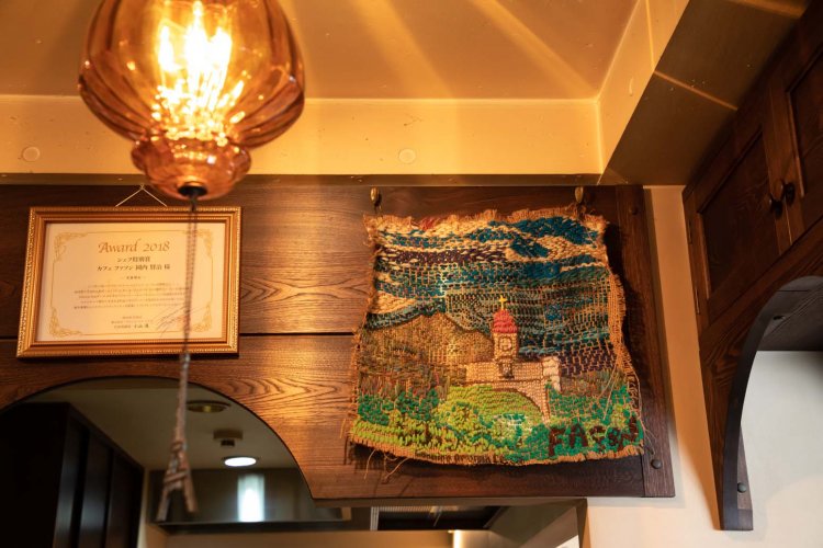 コーヒー豆の麻袋に刺繍ししている。絵画と同じ作家さんの作品。