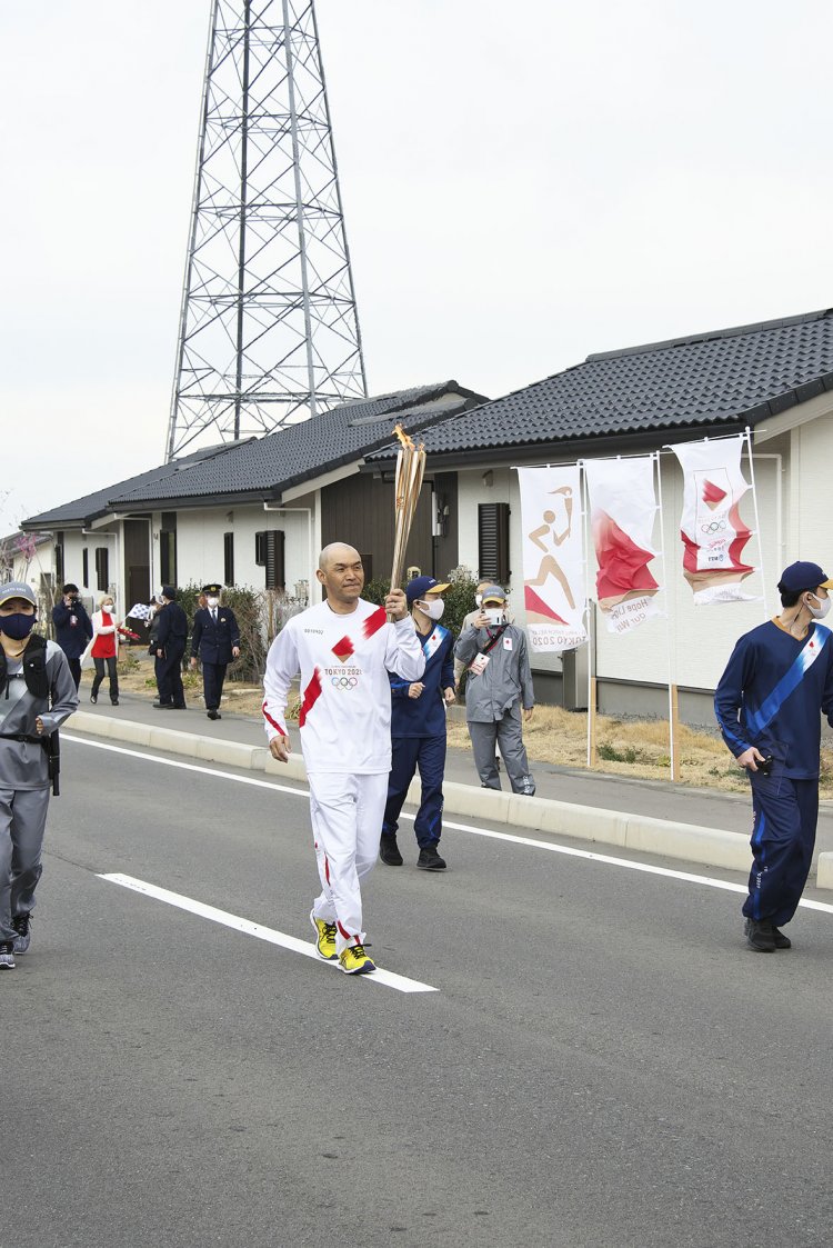 ようやく聖火ランナー登場。周りはセキュリティランナーが数人伴走。背後の建物は災害公営住宅。
