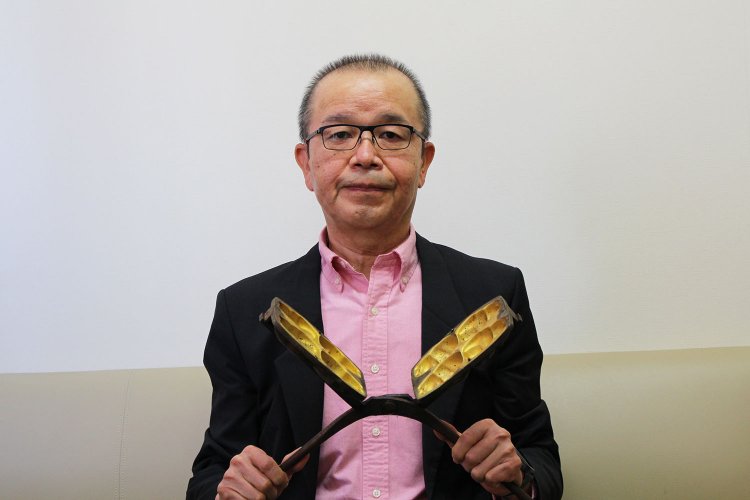 取締役専務の山田満さん。手にしているのは昔の手焼きの人形焼の型。