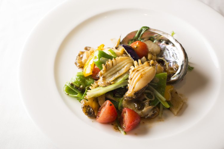 活蝦夷アワビと旬野菜の肝醤ソース炒め2700円。アワビは一皿に丸々１個。万願寺唐辛子、マコモタケなど旬野菜が彩りとアクセントを加える。