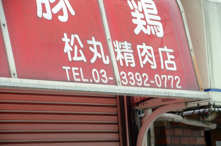 テントに注目して見ると……左端に「松丸精肉店」という表記が！