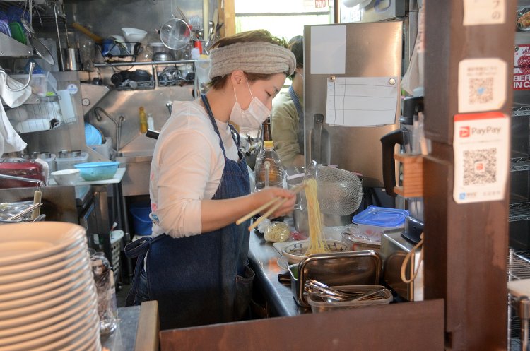 厨房での調理シーン。丁寧に麺を整える様子が印象的。