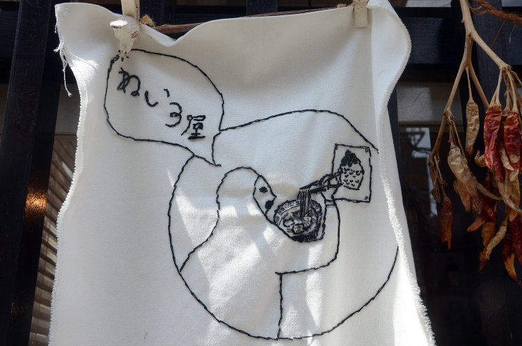 お店のロゴマークを海後さん自ら刺しゅうした味のあるタペストリー！