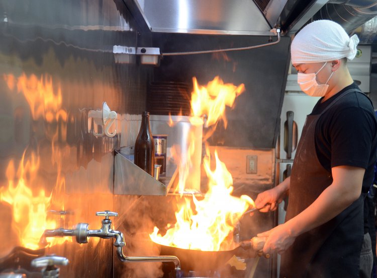 特製十八番の味を決めるニンニク炒めはオーダーと同時に調理開始。舞い上がる炎とともに中華鍋からは食欲をそそるいい香りが！