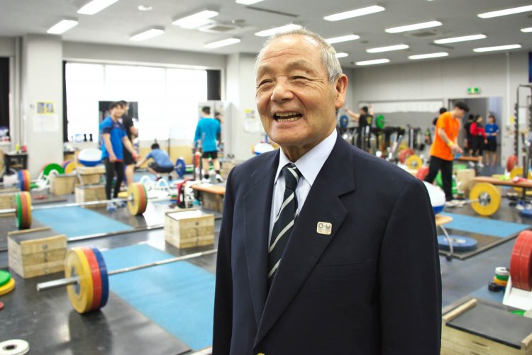 第一期生の三宅義信さんは体育学校校長も経験し、校内の体育館や植栽を整備した。現在は写真の東京国際大学ウエイトリフティング部監督。「生涯好きな道で幸せです」。