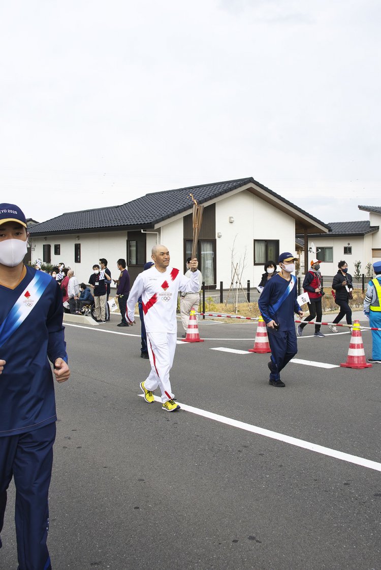 災害公営住宅前を走る聖火ランナー。