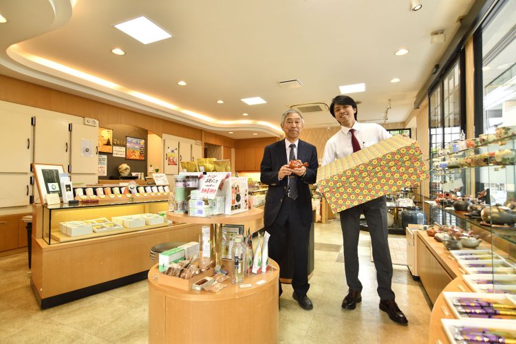 広々した売り場で、茶箱を持つ4代目と3代目（左）。