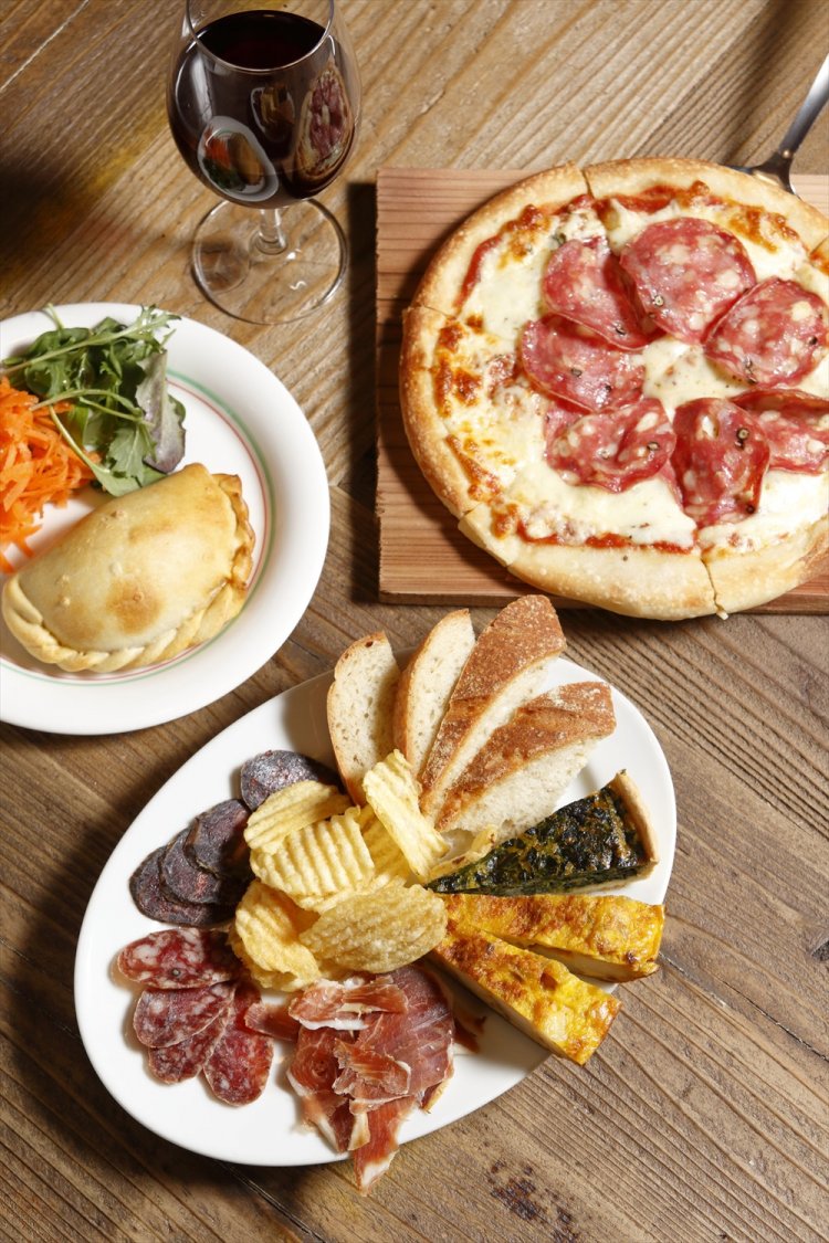 グラスワイン500円～、サラミのピザ950円、生ハムやキッシュなどを盛ったOkiyaの5つのフレーバー 1000円、アルゼンチン風のエンパナーダ400円。