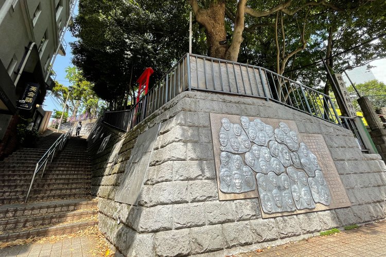 JR大森駅西口目の前の神明山天祖神社の下には、文士たちのレリーフが刻まれる。坂を登れば、かつての馬込文士村へ。