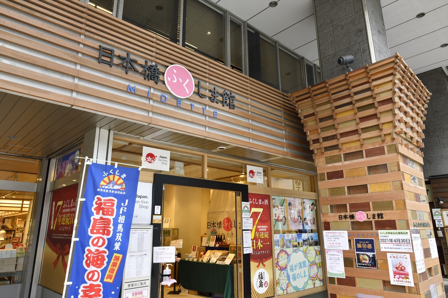 圧巻の日本酒コーナーで、名物の赤べこを持つ館長の小山勉さん。「いろんな酒蔵の酒をまずは一度飲まんしょ!」