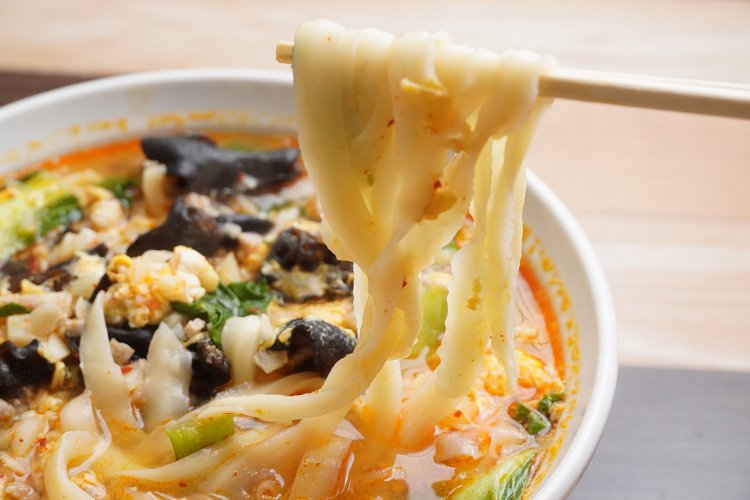 つるつるもっちりのニンニク刀削麺880円。幅広麺がよくスープに絡む。