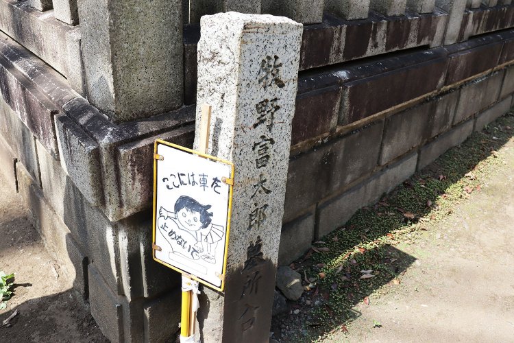 牧野富太郎博士の墓の方向を示す石碑。横に立つ手描きの看板が味わい深い。