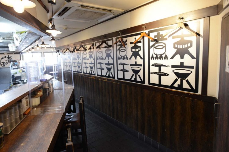 壁にずらりと並ぶのは、「東京煮干」の文字に、煮干しラーメン、東京タワーなどのモチーフを組みあわせたロゴ。