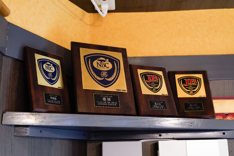 さりげなく棚の上にあるバス釣りの表彰盾。今時期は太刀魚とか、と話題が広がる。