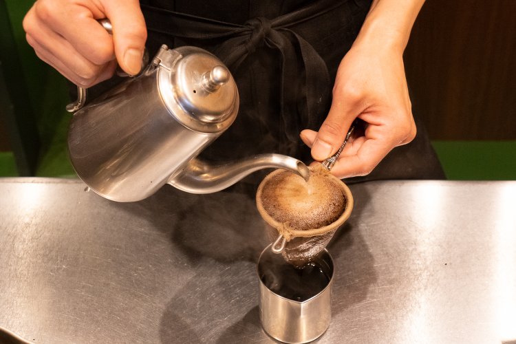 左手にネルドリッパー、右手にポット。ステンレスの計量カップに落としたコーヒーは、少しだけ火にかけてからお客さんに出す。