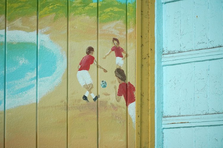 ペンキ絵の端に、サッカーをする子どもたち。もちろんユニフォームはレッズの赤だ。