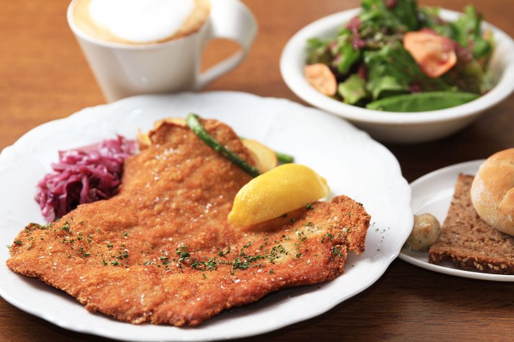 ドイツパンやサラダがつく豚フィレ肉のシュニッツェルのランチセット1600円。+150円でドリンクを写真のウィーン風カプチーノ･メランジェに変更可。