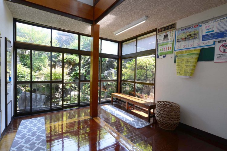 ガラス戸の向こうには池を備えた庭がある。長椅子の横に置かれた籐のカゴにも歴史が感じられる。