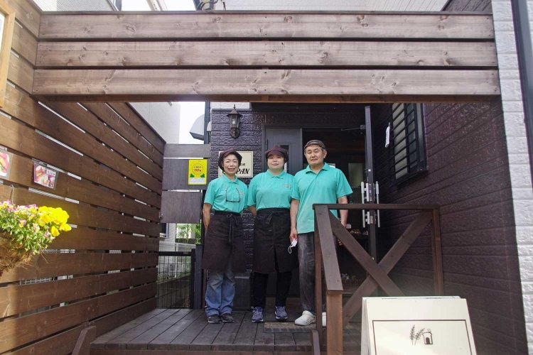 山小屋風に改装した入り口のウッドデッキに立つ比嘉さん一家。