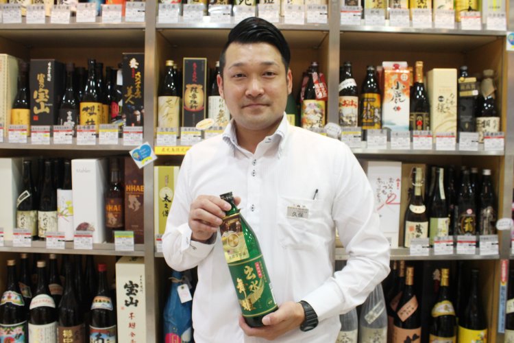 酒瓶がずらりと並ぶ、焼酎コーナーで待ち受ける副店長の久保さん。